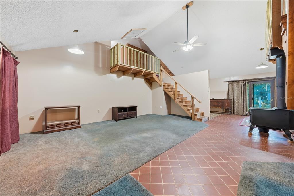 A living room features a loft area, wooden staircase, carpeted and tiled flooring, and stove — 163 E ORANGE AVENUE, PIERSON, FL