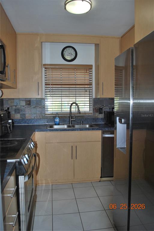 A kitchen features light wood cabinets, stainless steel appliances, a tile backsplash, and tile flooring — 1515 NEBRASKA AVENUE, PALM HARBOR, FL