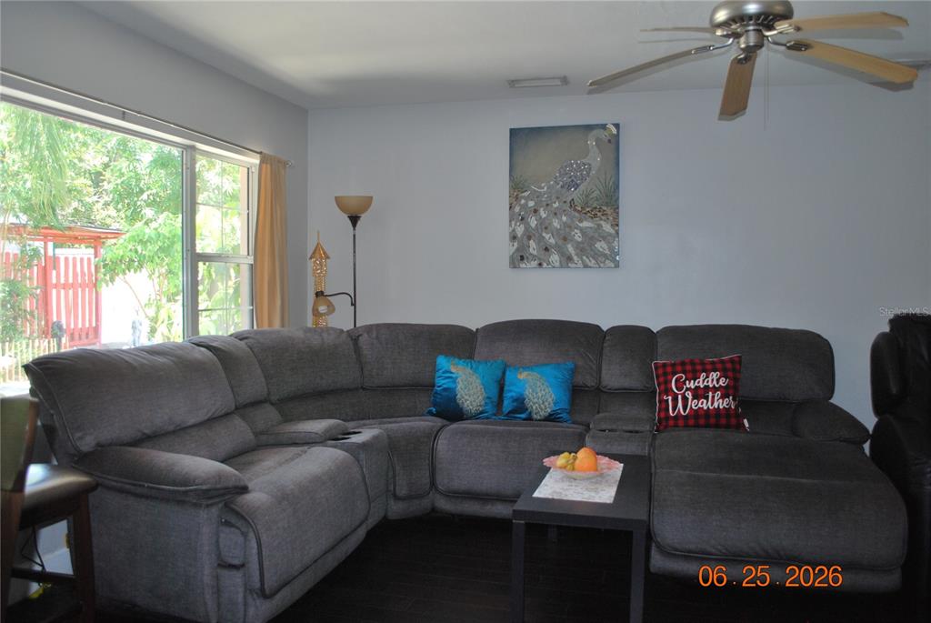 A living room features a large gray sectional sofa, a ceiling fan, and a peacock painting — 1515 NEBRASKA AVENUE, PALM HARBOR, FL