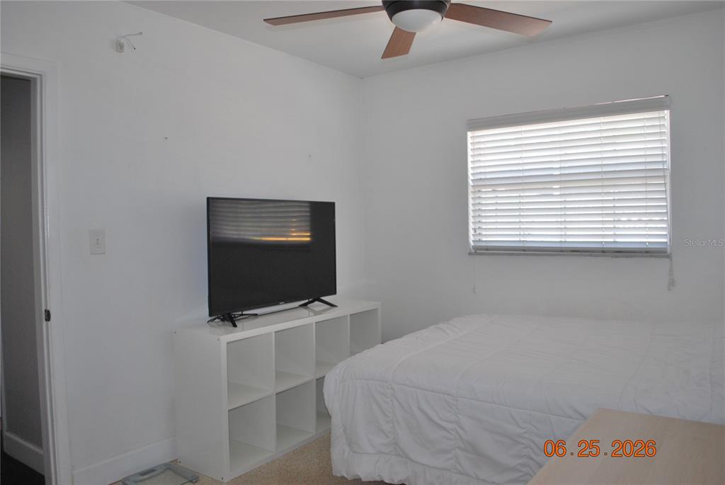 A bedroom features white walls, a ceiling fan, a television on a white shelf, and a bed — 1515 NEBRASKA AVENUE, PALM HARBOR, FL
