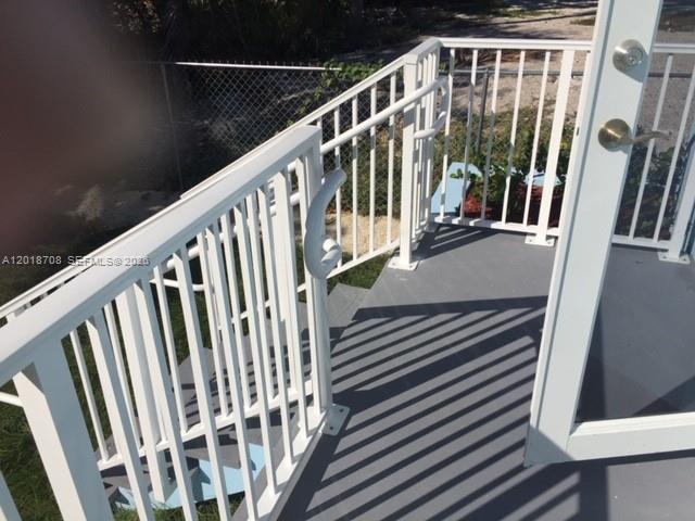 An outdoor deck with white metal railings and stairs leading down to a grassy yard — 265 15th St # B, Marathon FL 33050, MARATHON, FL