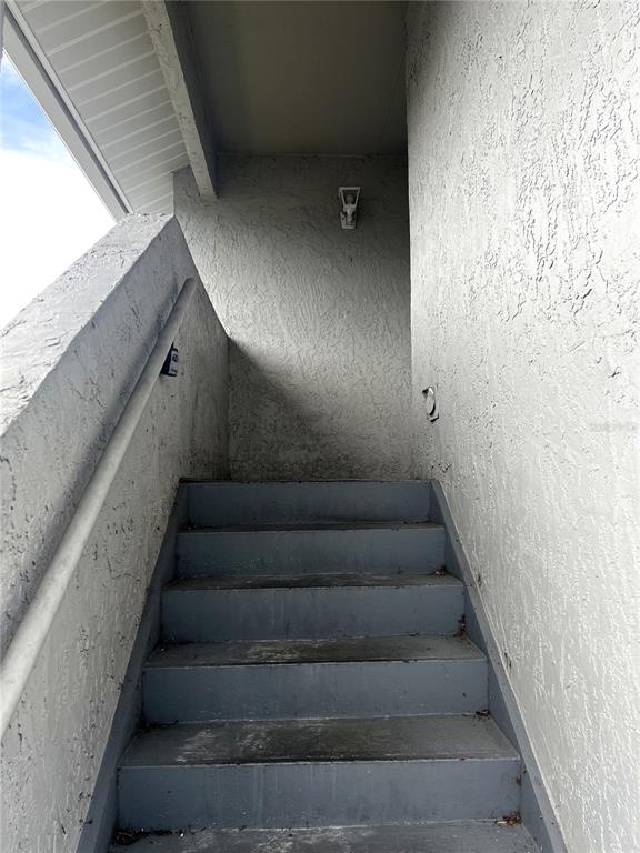 An outdoor staircase with gray painted steps and a metal handrail leads to a landing — 4400 WHITE PINE AVENUE UNIT 70-4, ORLANDO, FL