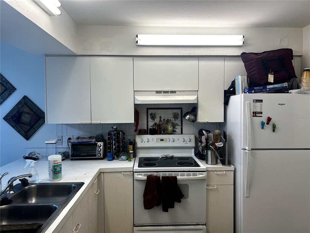 A kitchen features white cabinets, a white stove, a double sink, and a white refrigerator — 4400 WHITE PINE AVENUE UNIT 70-4, ORLANDO, FL