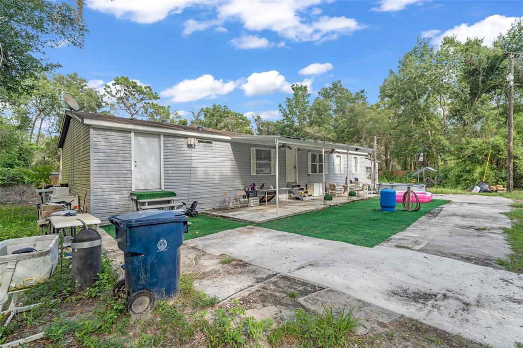 The exterior of a single-story house features light gray siding, a concrete patio, and turf — 15816 NORTHGATE LANE, SPRING HILL, FL