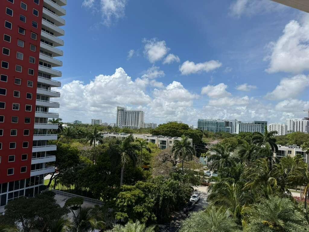 An elevated view of a city skyline with palm trees and a red apartment building — 1581 Brickell Avenue # 406, Miami FL 33129, MIAMI, FL