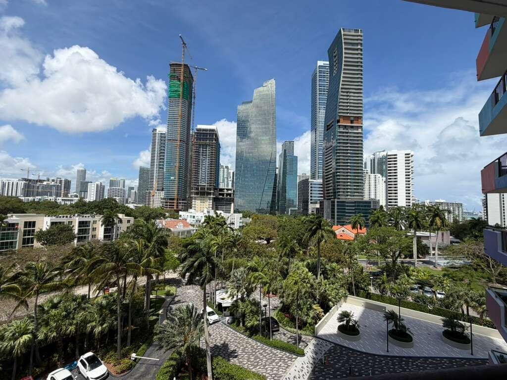 An elevated view of a city skyline featuring several skyscrapers rising above a lush park — 1581 Brickell Avenue # 406, Miami FL 33129, MIAMI, FL