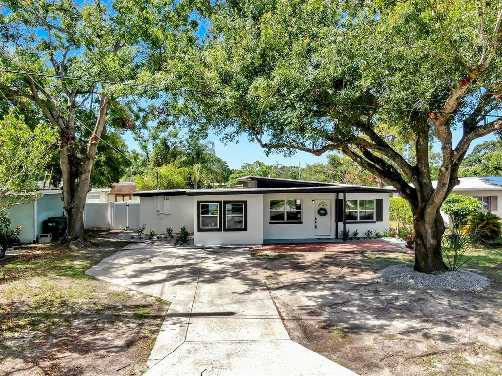 A single-story white house with a flat roof and dark trim sits behind a concrete driveway — 4112 W LAWN AVENUE, TAMPA, FL
