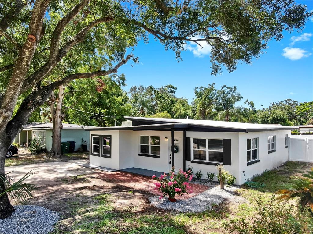 A single-story white house with a flat roof, black trim, and a brick front patio — 4112 W LAWN AVENUE, TAMPA, FL