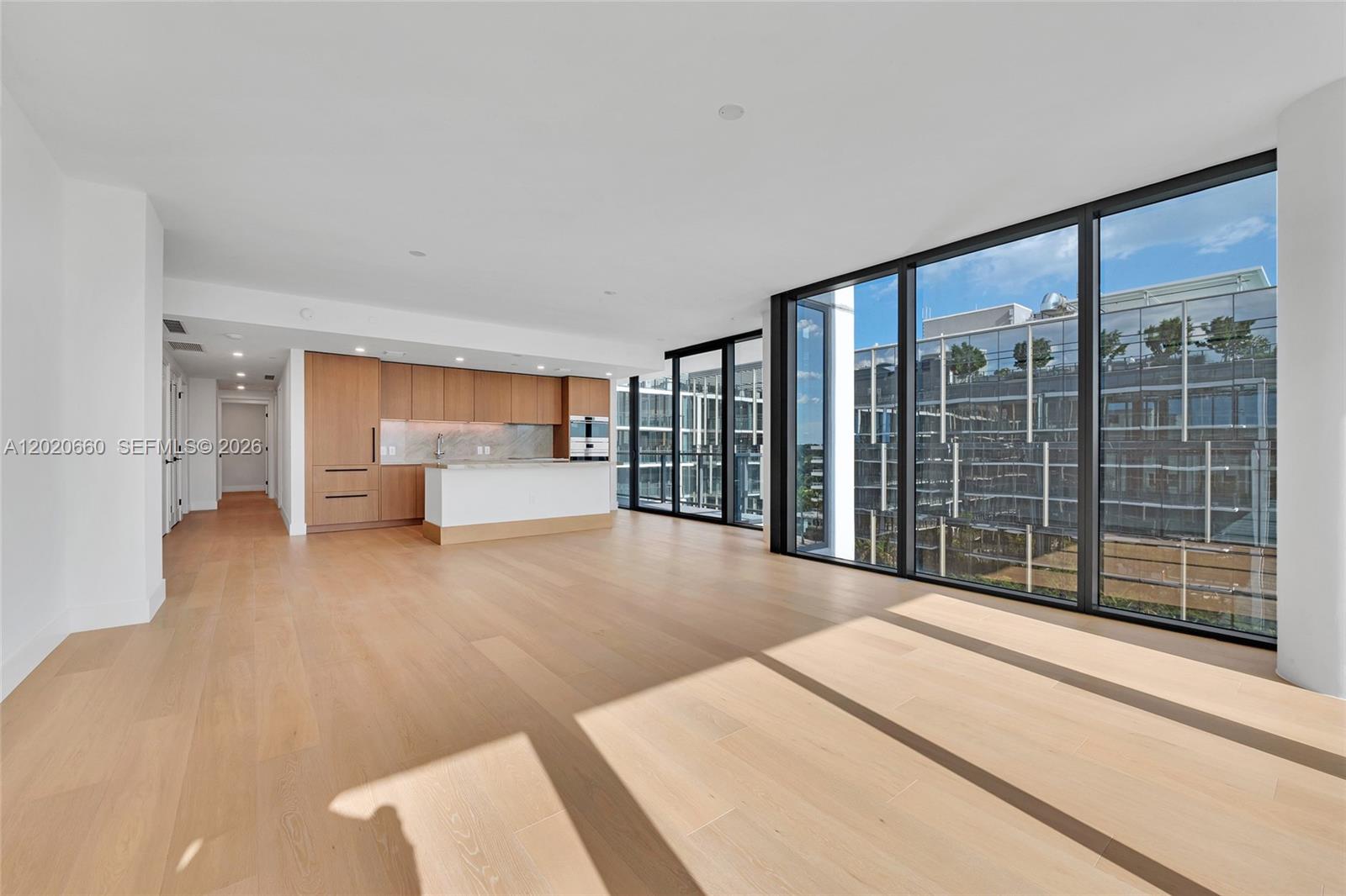 A modern kitchen features light wood cabinetry, marble countertops, and a large window with city views — 1176 97th St # 704, Bay Harbor Islands FL 33154, BAY HARBOR ISLANDS, FL