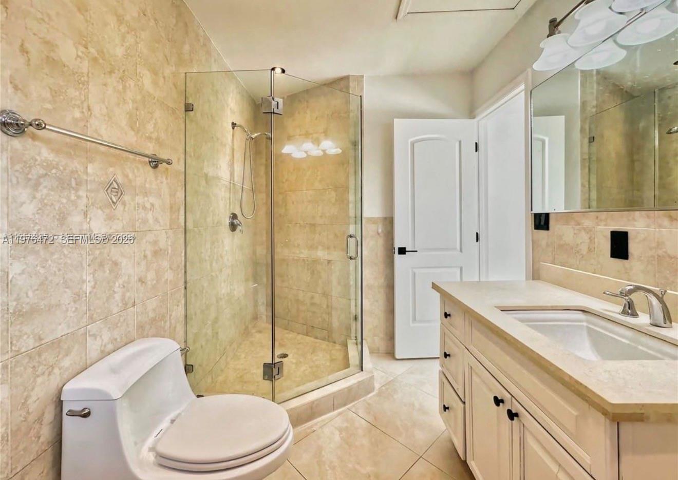 A bathroom features a glass-enclosed shower, a white vanity with a sink, and beige tile — 21020 NE 18th Ct, Miami FL 33179, MIAMI, FL