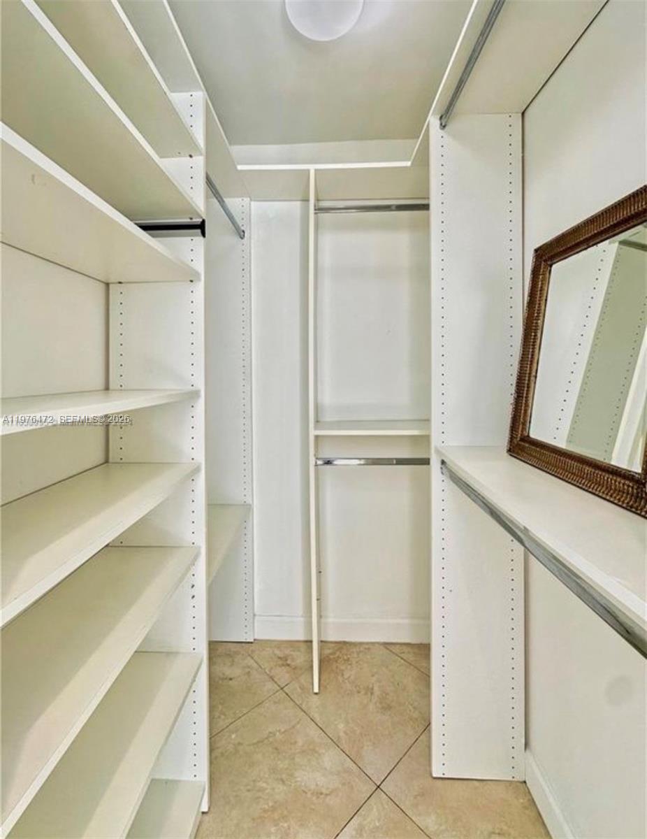 A walk-in closet features white shelving, hanging rods, and a mirror on the wall — 21020 NE 18th Ct, Miami FL 33179, MIAMI, FL