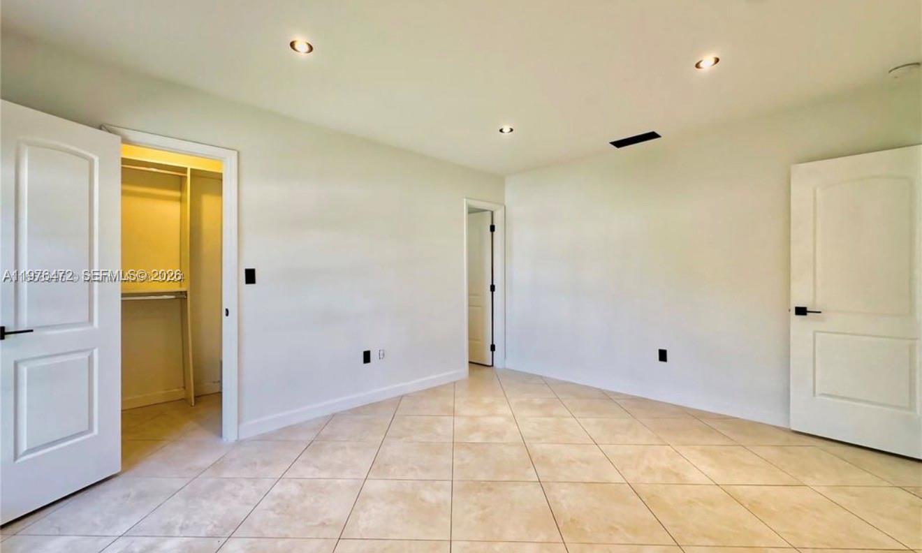 A bedroom with light-colored tile flooring, recessed lighting, and two interior doors — 21020 NE 18th Ct, Miami FL 33179, MIAMI, FL