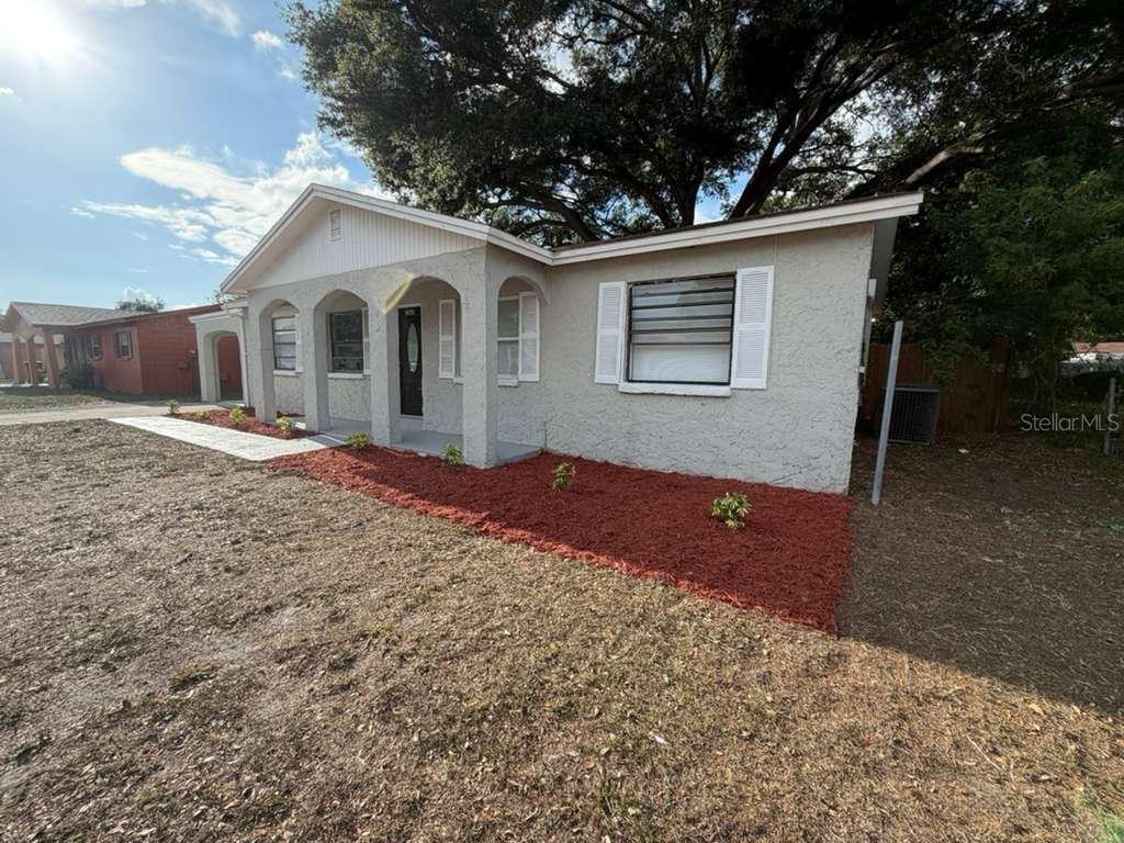 A single-story house with a stucco exterior, arched porch entry, and red mulch landscaping — 2065 BALFOUR CIRCLE, TAMPA, FL