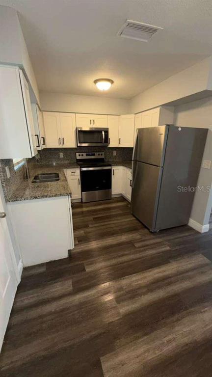 A kitchen features white cabinets, granite countertops, stainless steel appliances, and wood-look flooring — 2065 BALFOUR CIRCLE, TAMPA, FL