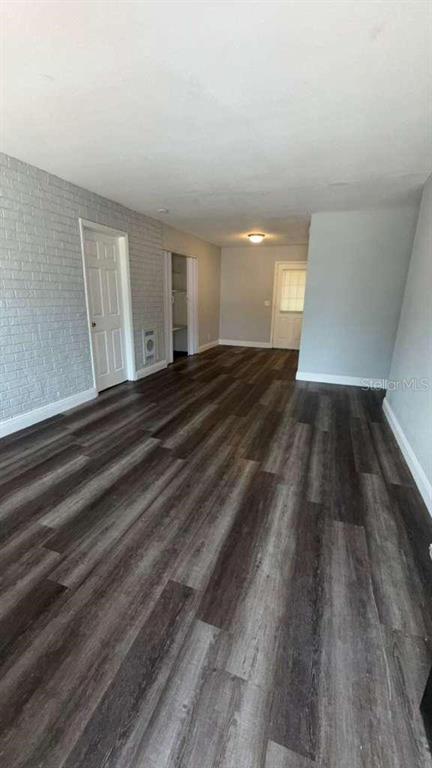 A room with dark wood-look flooring, a white brick wall, and two white interior doors — 2065 BALFOUR CIRCLE, TAMPA, FL