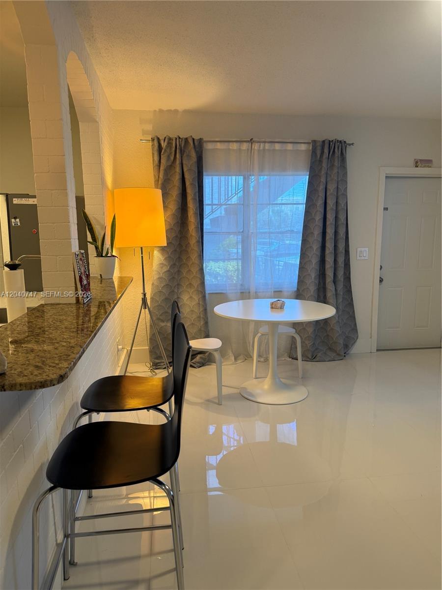 A dining area with a white table, two black bar stools, and a floor lamp — HOLLYWOOD, FL