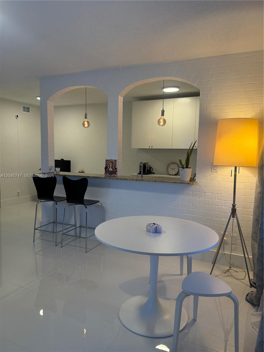 A dining area features a white table, two black bar stools, and arched kitchen pass-throughs — HOLLYWOOD, FL