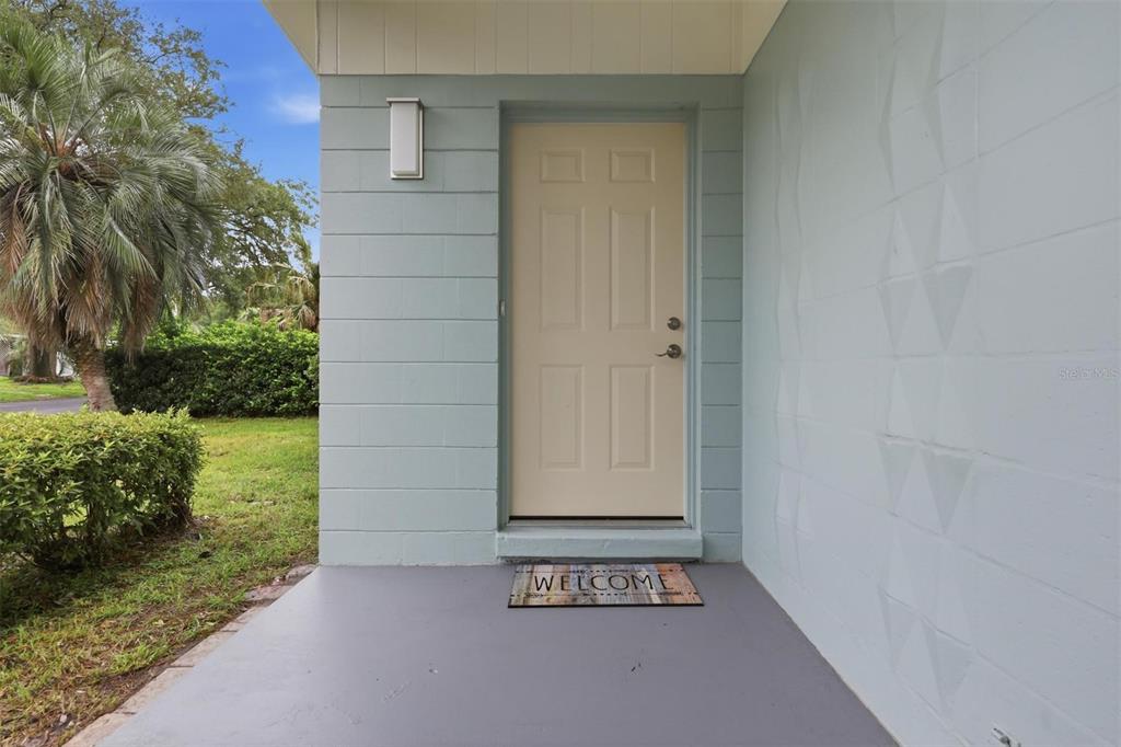 A light blue exterior wall features a beige front door and a welcome mat — 2832 NE 11TH TERRACE, GAINESVILLE, FL