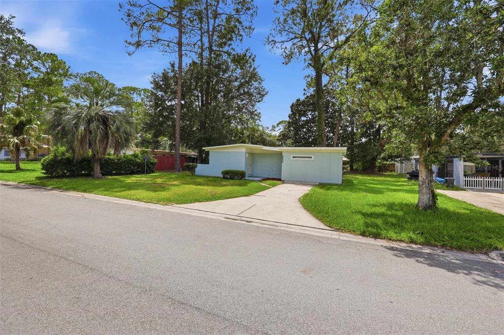 A light blue, single-story house with a flat roof sits on a grassy corner lot — 2832 NE 11TH TERRACE, GAINESVILLE, FL