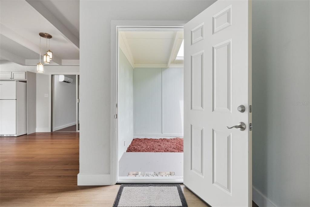 An open white door leads from a room with wood flooring to an enclosed porch — 2832 NE 11TH TERRACE, GAINESVILLE, FL