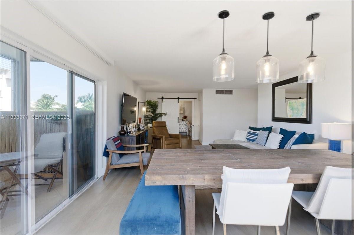 A dining area with a wooden table and blue bench opens into a living room — 550 Ocean Drive # 3H, Key Biscayne FL 33149, KEY BISCAYNE, FL