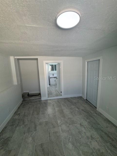 A room with gray tile flooring, a ceiling light, and a doorway leading to a bathroom — 330 S. BUENA VISTA AVENUE, ORLANDO, FL