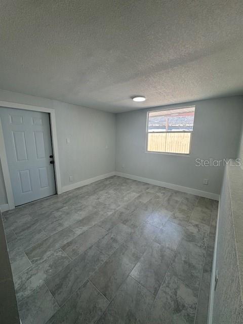 An empty room features gray tile flooring, light gray walls, a window, and a door — 330 S. BUENA VISTA AVENUE, ORLANDO, FL