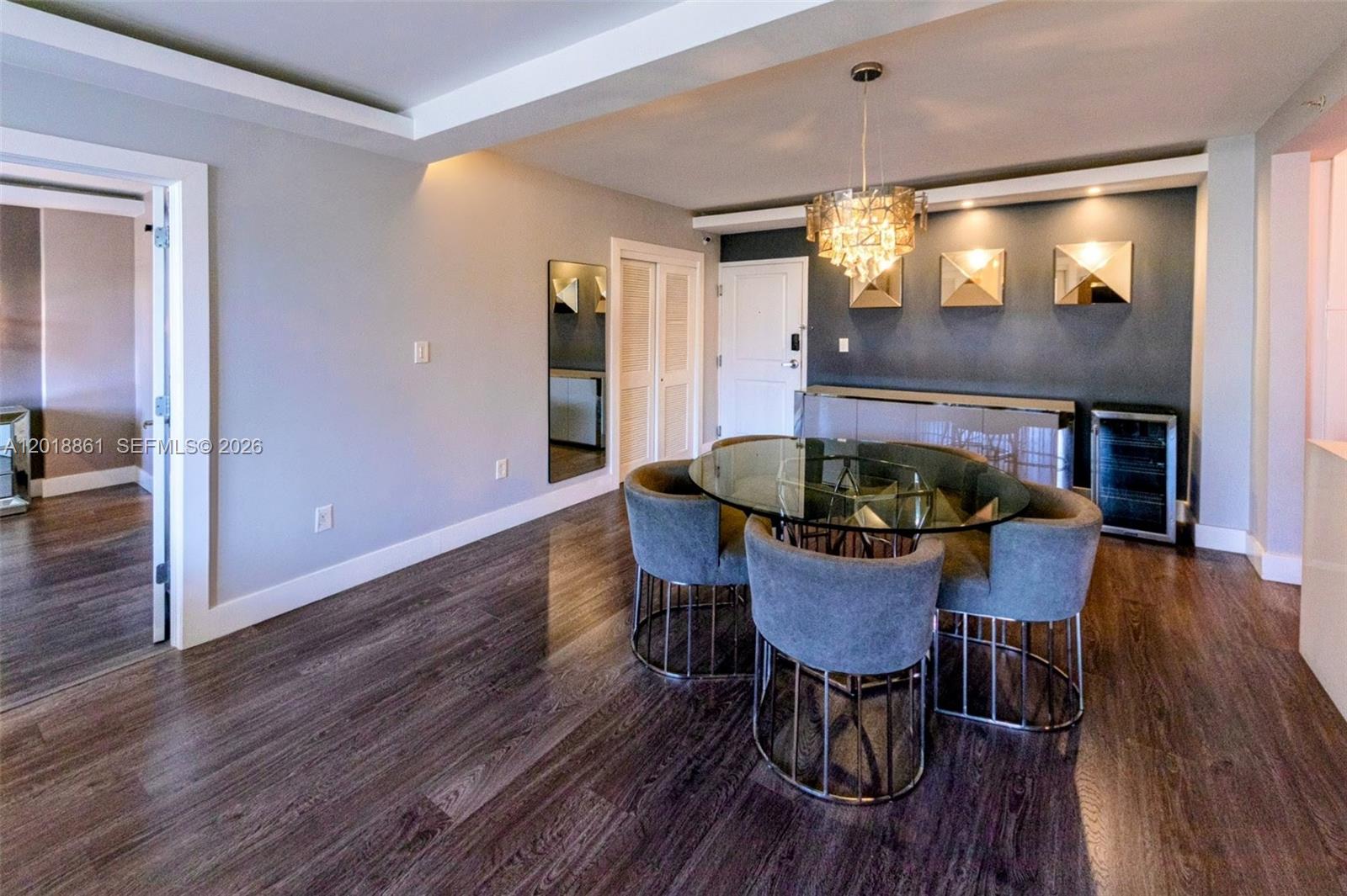 A dining room features a glass table, gray upholstered chairs, and a dark accent wall — 401 69th St # 212, Miami Beach FL 33141, MIAMI BEACH, FL