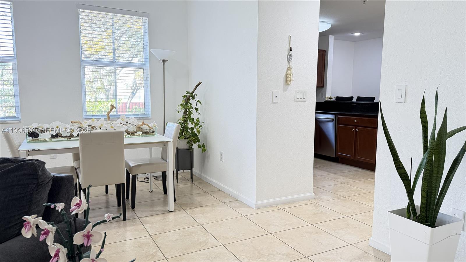 A dining area with a white table and chairs sits adjacent to a kitchen — 11605 NW 89th St # 220, Doral FL 33178, DORAL, FL