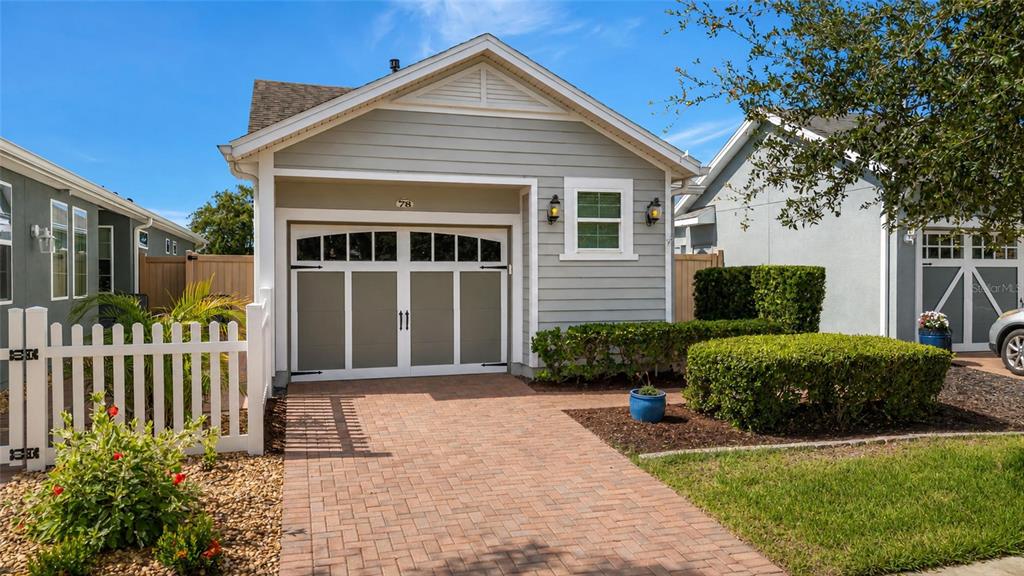 A light gray house with a brick driveway, a white picket fence, and a garage — 78 BAYOU BEND ROAD, GROVELAND, FL