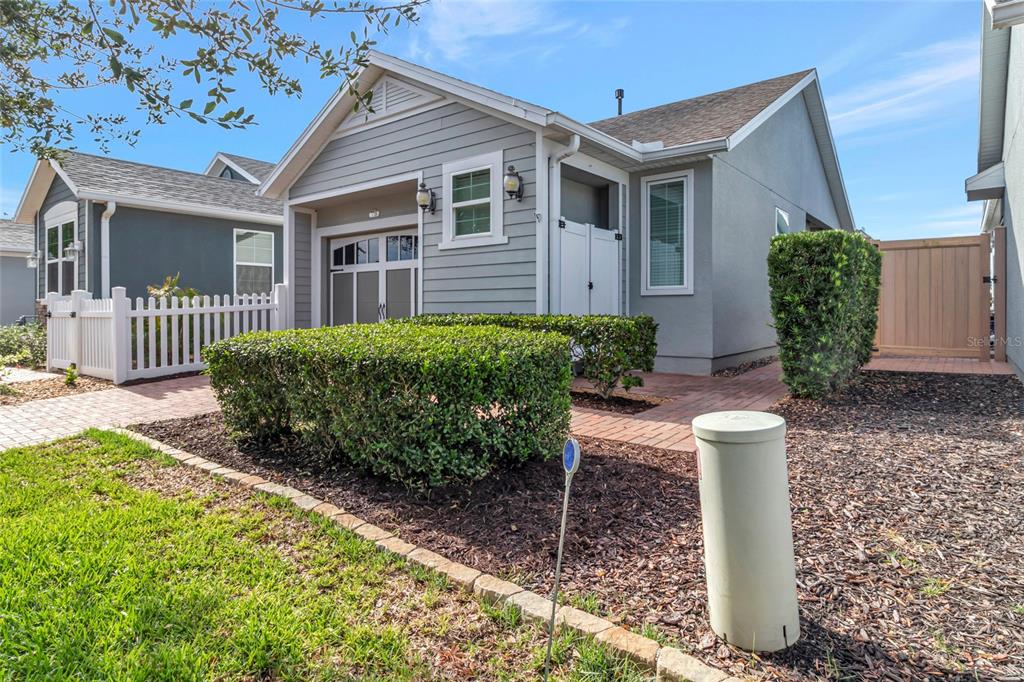 A gray house with a brick walkway, white picket fence, and manicured hedges in front — 78 BAYOU BEND ROAD, GROVELAND, FL