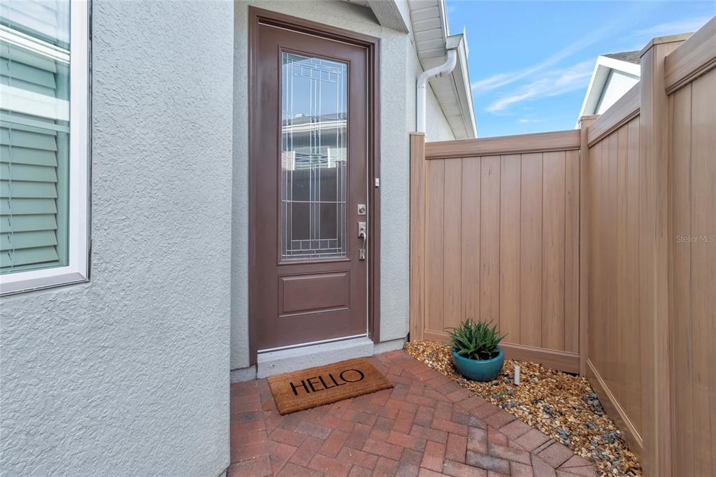 A brown front door with a glass insert sits beside a tan privacy fence — 78 BAYOU BEND ROAD, GROVELAND, FL