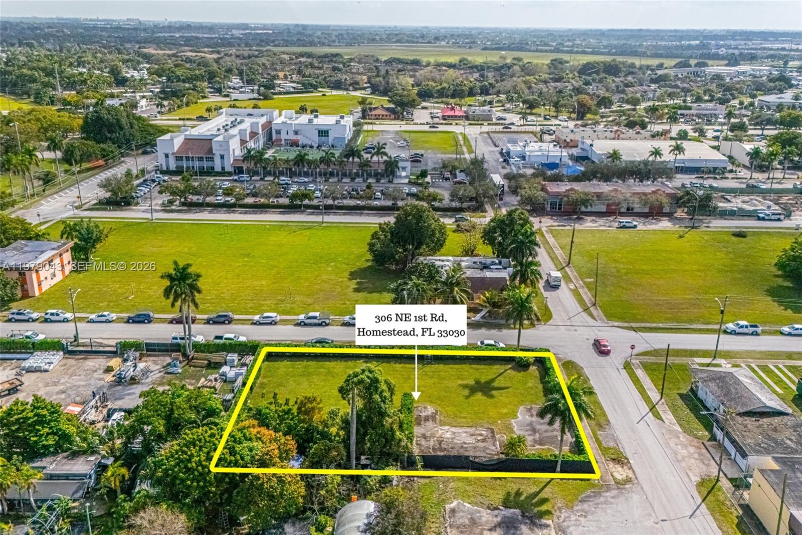 An aerial view shows a vacant, fenced rectangular lot with a concrete foundation and trees — 306 NE 1st Rd, Homestead FL 33030, HOMESTEAD, FL