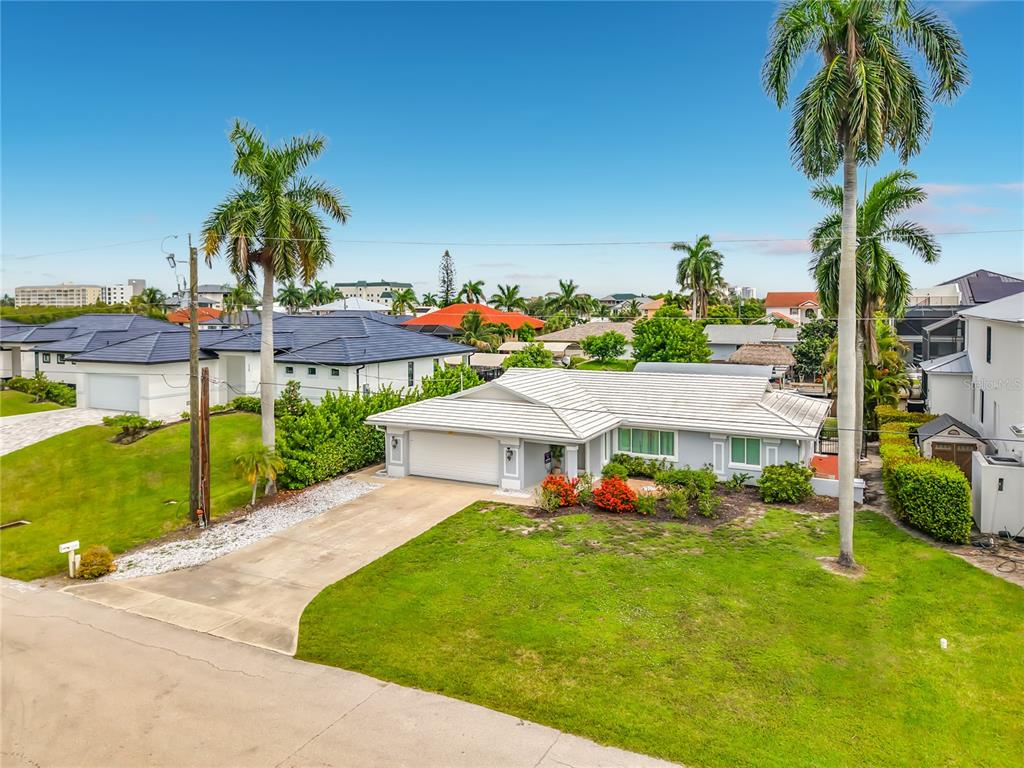 An aerial view of a single-story house with a white roof, garage, and palm trees — 225 3RD STREET, BONITA SPRINGS, FL