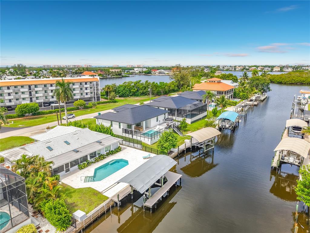 An aerial view shows waterfront houses with swimming pools, boat docks, and canal access — 225 3RD STREET, BONITA SPRINGS, FL