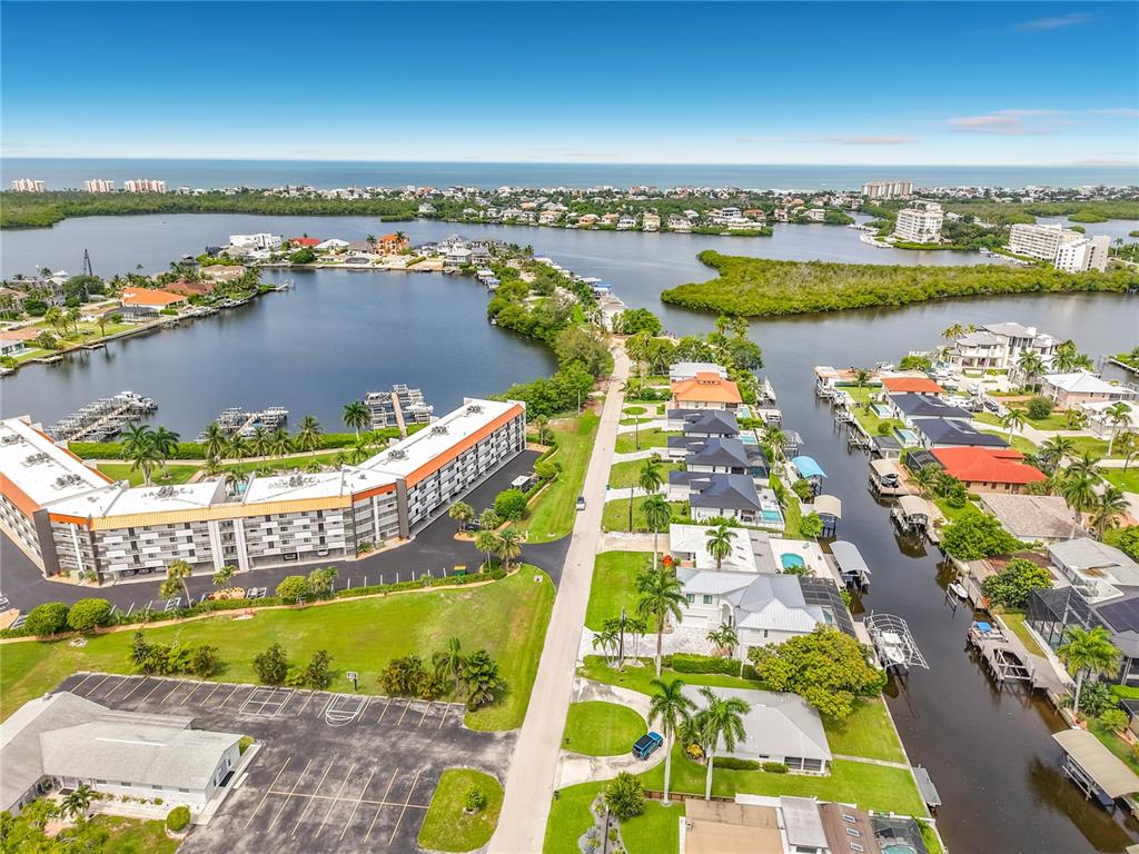 An aerial view shows a waterfront residential area with a large apartment complex and houses — 225 3RD STREET, BONITA SPRINGS, FL