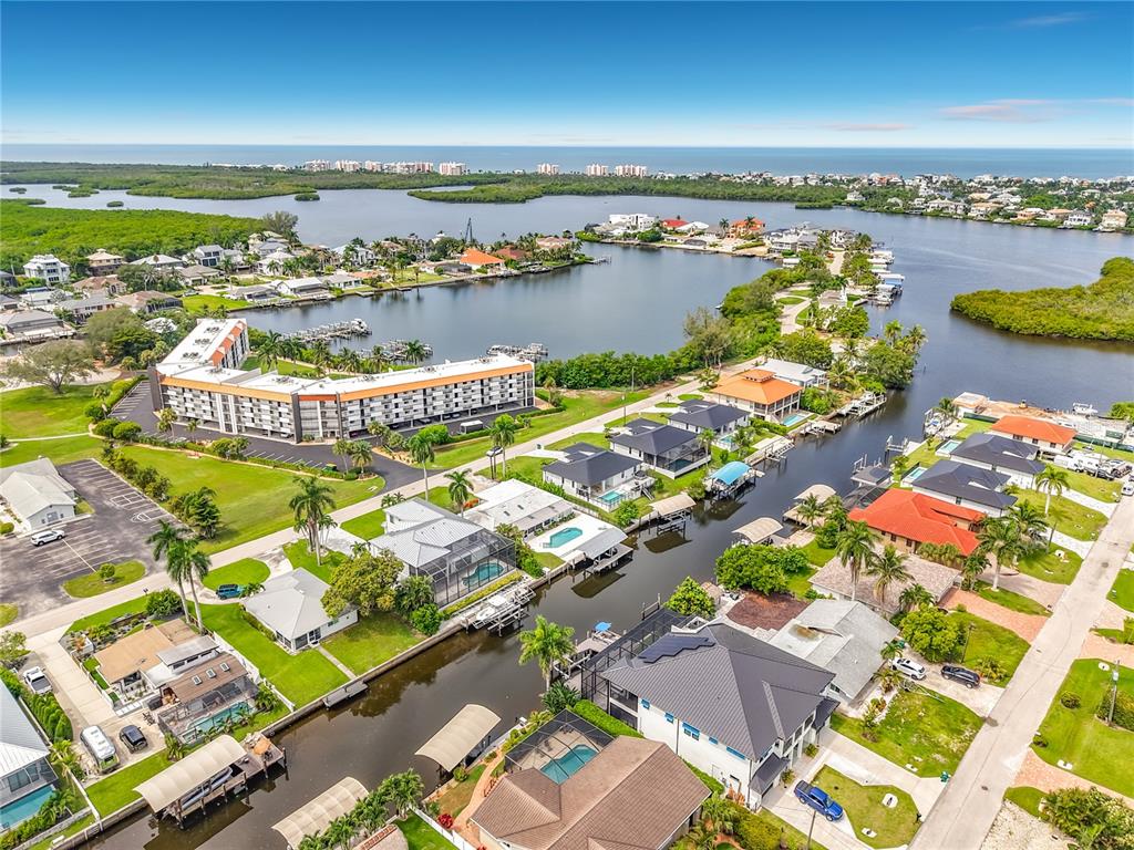 An aerial view shows a residential neighborhood with houses along a canal near the ocean — 225 3RD STREET, BONITA SPRINGS, FL