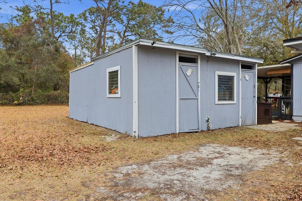 A light blue detached storage shed with two doors and two windows sits outdoors — 6771 W SASSER STREET, HOMOSASSA, FL