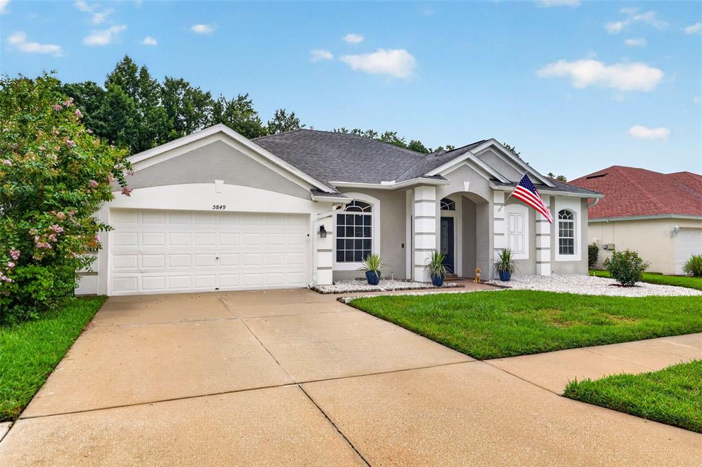 A single-story suburban house features a two-car garage, a paved driveway, and a front lawn — 5849 RIVA RIDGE DRIVE, WESLEY CHAPEL, FL