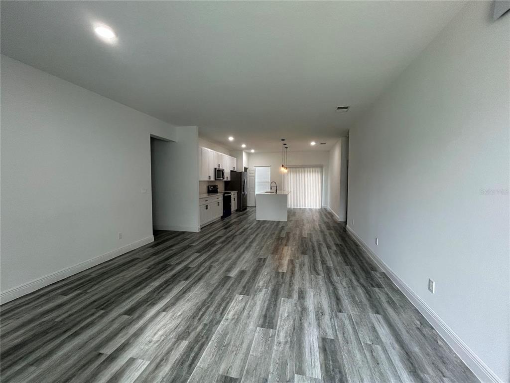 An open-concept living area features light gray walls, wood-look flooring, and a kitchen with white cabinets — 14445 SW 42ND TERRACE ROAD, OCALA, FL