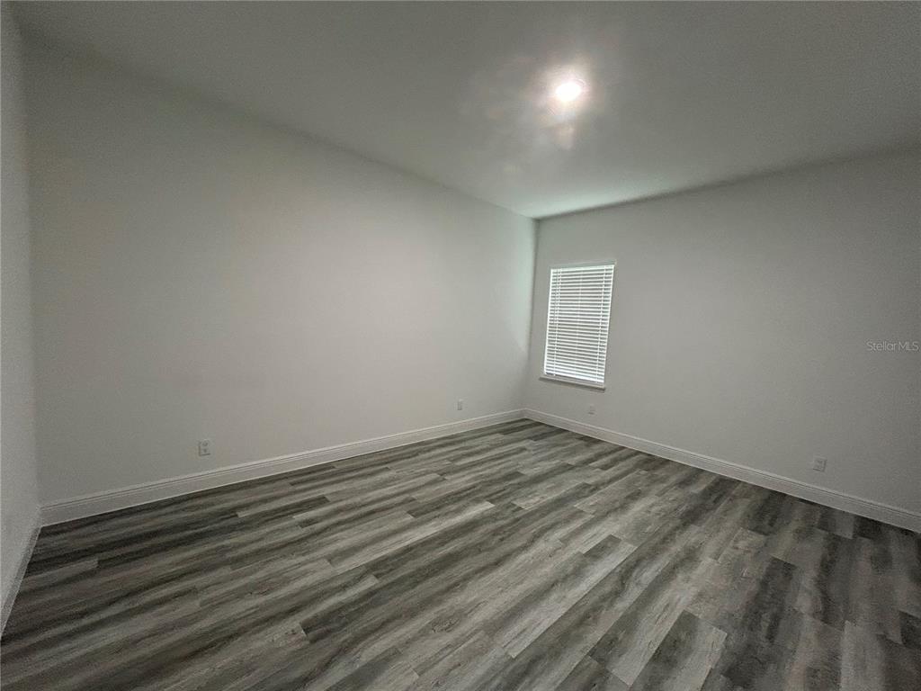 An empty room features light gray walls, white trim, and wood-look vinyl plank flooring — 14445 SW 42ND TERRACE ROAD, OCALA, FL