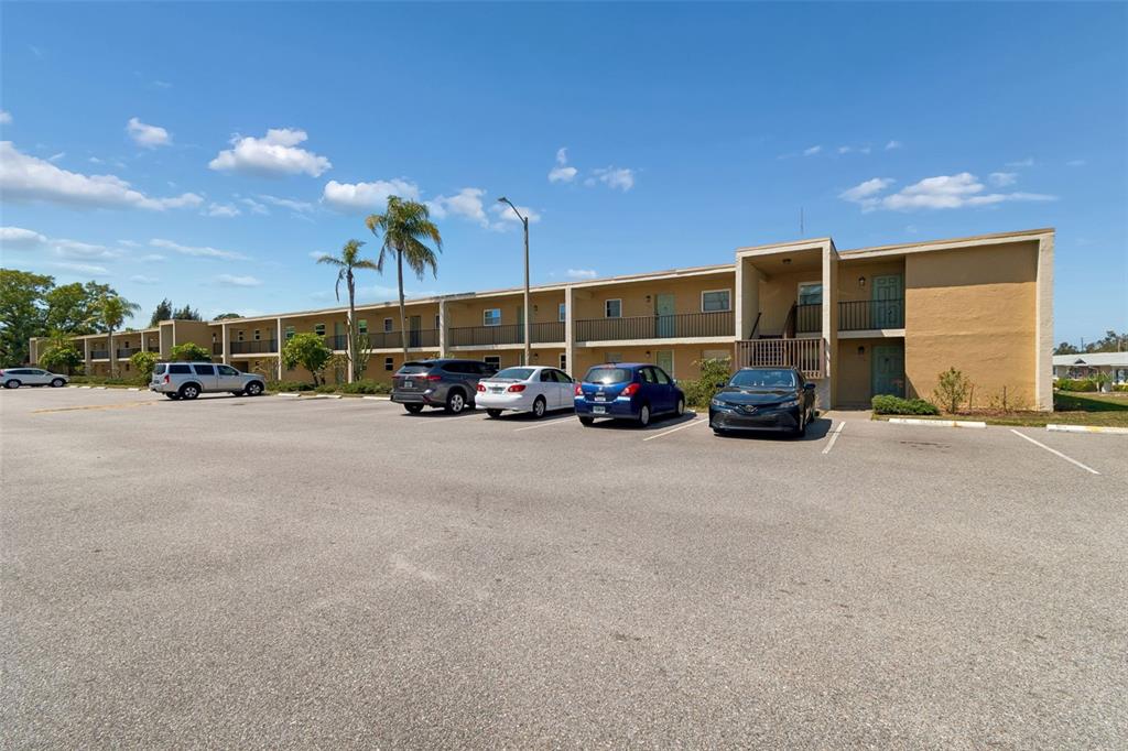 A two-story tan apartment building with an asphalt parking lot in the foreground — 12300 PARK BOULEVARD UNIT 221, SEMINOLE, FL