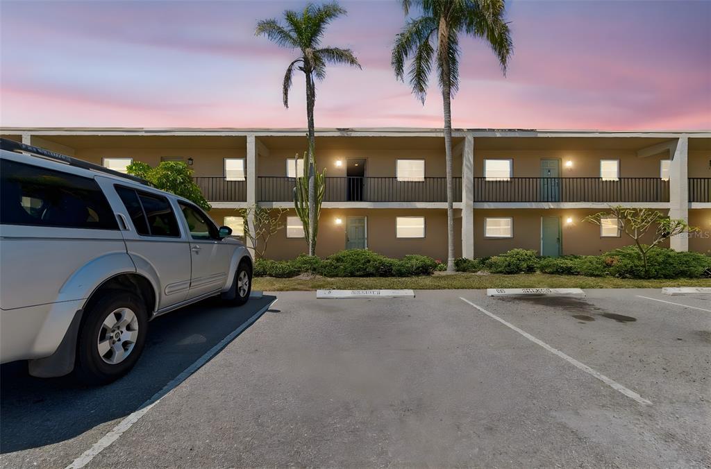 A silver SUV is parked in front of a two-story apartment building at sunset — 12300 PARK BOULEVARD UNIT 221, SEMINOLE, FL