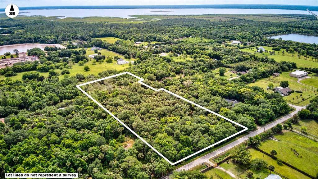 An aerial view shows a wooded, rectangular lot outlined in white next to a road — S MELLONVILLE AVENUE, SANFORD, FL
