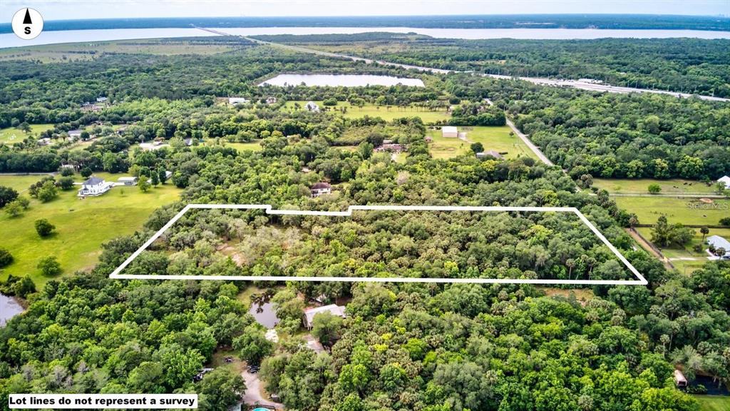 An aerial view shows a rectangular plot of land outlined in white amidst wooded terrain — S MELLONVILLE AVENUE, SANFORD, FL
