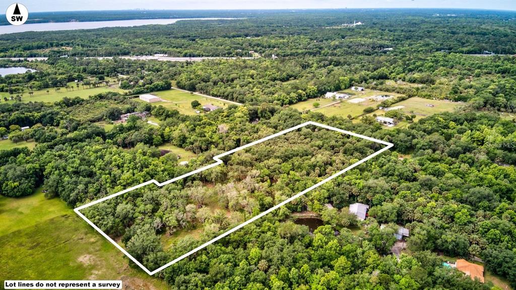 An aerial view shows a rectangular plot of land outlined in white amidst dense forest — S MELLONVILLE AVENUE, SANFORD, FL