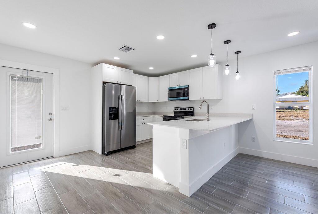 A modern kitchen features white cabinets, stainless steel appliances, and a white quartz island — 3018 SE Iris Street # 1, Stuart FL 34997, STUART, FL