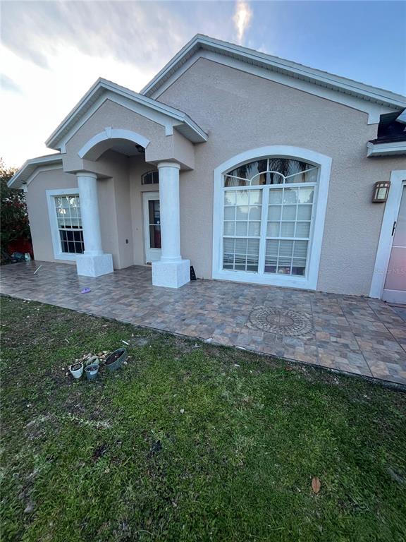 A beige stucco house features a tiled front porch with two white columns — 823 OGNON COURT, KISSIMMEE, FL