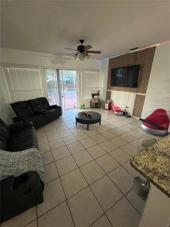 A living room features tile flooring, a ceiling fan, and a wall-mounted television — 823 OGNON COURT, KISSIMMEE, FL