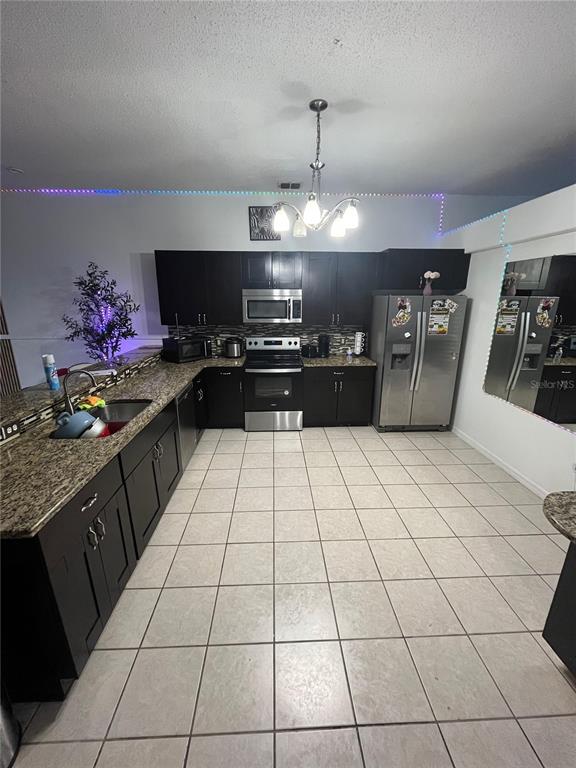 A kitchen features dark wood cabinets, granite countertops, stainless steel appliances, and tiled flooring — 823 OGNON COURT, KISSIMMEE, FL